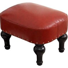 a red leather ottoman sitting on top of a black wooden footstool with studded legs