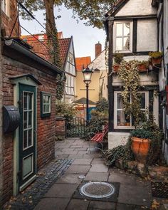 an alley way with brick buildings and potted plants on either side, surrounded by greenery