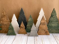 small wooden christmas trees lined up against a brown wall with snow flakes on them