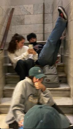 three people are sitting on the stairs and taking pictures with their cell phones in front of them