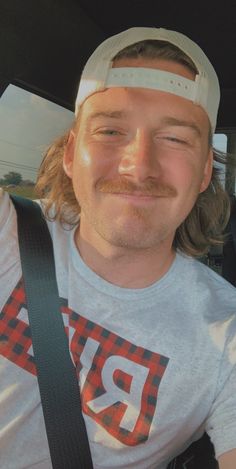 a man sitting in the back seat of a car wearing a blindfold and smiling