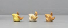 three small figurines in the shape of hands holding something yellow, white and black