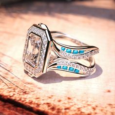 a diamond and turquoise ring sitting on top of a wooden table