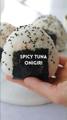 there is a hand holding some kind of sushi with black sesame sprinkles on it