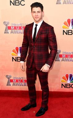 a young man in a suit and tie on the red carpet at an awards event