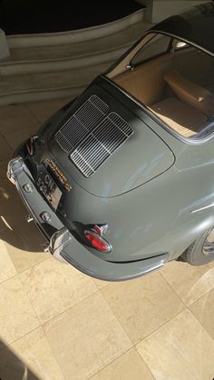 an old car is parked on the floor in front of a building with stairs leading up to it