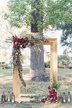 a wedding arch decorated with flowers and greenery for an outdoor ceremony in the woods