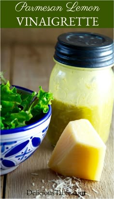 a bowl of lettuce and cheese next to a jar of mustard on a wooden table