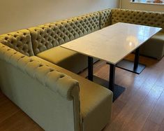 a couch and table in a room with hardwood floors, windows, and white walls