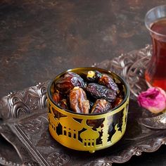 a bowl of dates next to a cup of tea