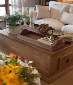 a living room filled with lots of furniture and flowers on top of a coffee table