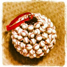 a baseball ornament with a red ribbon hanging from it's center on a table