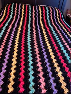 a multicolored crocheted afghan on a bed