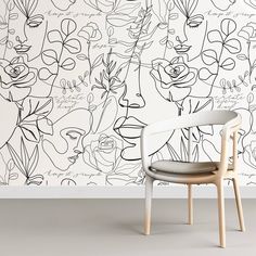 a chair sitting in front of a wall with flowers on it and writing all over the wall