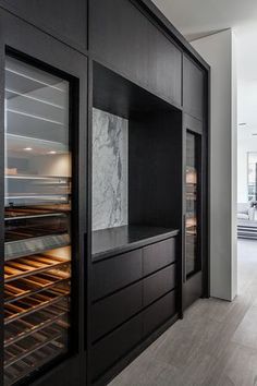 an empty kitchen with marble counter tops and black cabinets, along with large ovens