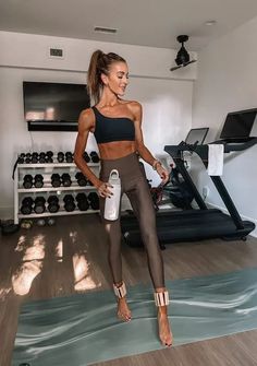 a woman standing on a yoga mat holding a water bottle