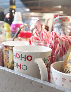 mugs and candy canes are sitting on a shelf in a store display case