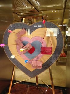 a heart shaped display with purses and bags on it in a store front window