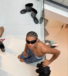 a man wearing sunglasses standing next to a skateboard on top of a white wall