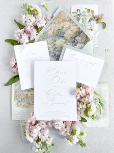 the wedding stationery is laid out on top of each other and surrounded by flowers