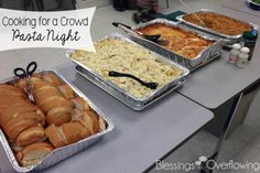 three trays of food sitting on top of a table with words cooking for a crowd pasta night