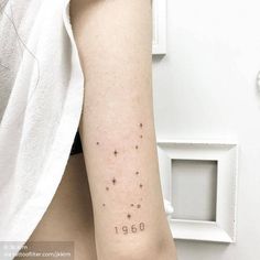 a woman's arm with numbers and stars tattooed on the back of her left arm