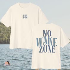 Lake days are here!!😎☀ It's the season for pontoons and High Noons and we have the perfect Oversized Tee to get you ready. Lay back, relax and be your best Lake Bum self this summer in our Oversized Lake Bum Comfort Colors Tee!✌ This simple, yet classic design is made with a calming blue unisex font meant to worn by anyone FRONT DESIGN: "Lake Bum" BACK DESIGN: "No Wake Zone" ☀ Relaxed Fit ☀Unisex - Comfort Colors ☀ Also available in Gildan Tshirts & Crewnecks, Canvas Totes, Trucker Hats, Bucket Hats, Koozies, and more!! Comfort & Style: Our apparel is crafted with premium quality materials, ensuring a soft and comfortable fit for day-long adventures. Customizable Location: Add your go-to lake spot to the design to make it all your own! Free Personalization: Headed to a family reunion on t Summer Crew Neck Top For Weekend, Summer Graphic Tee For Weekend, Graphic Print T-shirt For Summer Weekends, Light Blue Summer Vacation T-shirt, Light Blue Oversized Tshirt, Weekend Graphic Print Short Sleeve T-shirt, Summer Light Blue T-shirt With Logo Print, Light Blue Cotton T-shirt For The Beach, No Wake Zone