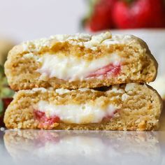 two strawberry shortcakes stacked on top of each other with icing and strawberries in the background