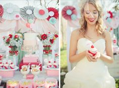 a woman in a white dress holding a cupcake and standing next to a table full of desserts