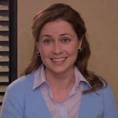 a smiling woman in a blue shirt and white collared shirt is looking at the camera