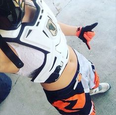 a woman in an orange and white uniform is holding a baseball glove on her hip