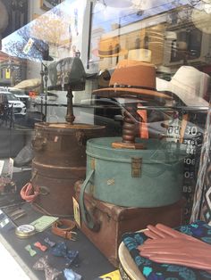 many hats and suitcases are on display in the window