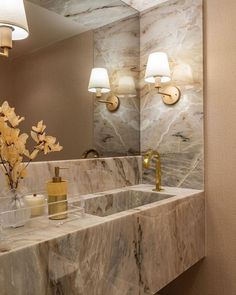 a bathroom with marble counter tops and gold fixtures