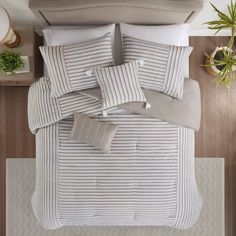 an overhead view of a bed with white and grey striped comforter, pillows and pillow cases