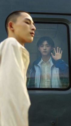 a man standing in front of a train window with his hand up to the side