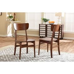 two wooden chairs sitting next to each other on top of a rug