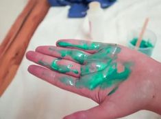 a person's hand with green paint on it