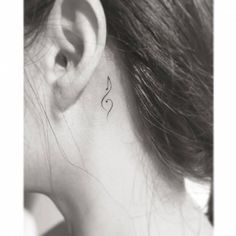 a woman's behind the ear has a small musical note tattoo on her left side