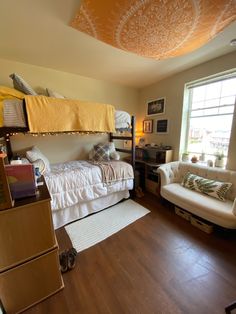 a loft bed sitting next to a couch in a living room on top of a hard wood floor