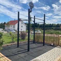 an outdoor gym in the middle of a yard with a fence around it and a street sign on top