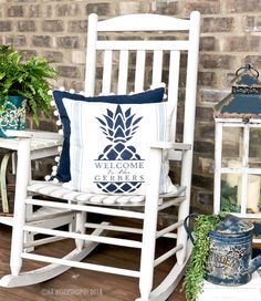 a white rocking chair sitting on top of a wooden floor next to a potted plant