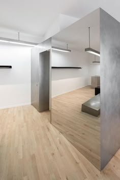 an empty room with wooden floors and metal partitions on the wall, in front of white walls