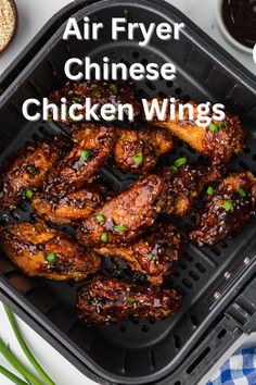 air fryer chicken wings in a black container with green onions and seasoning on the side