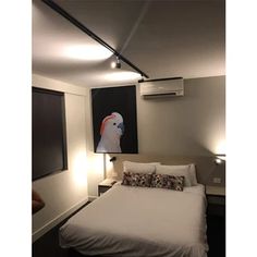 a white bed sitting in a bedroom next to a painting on the wall above it