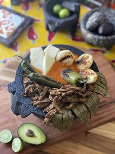 a wooden cutting board topped with food on top of a table next to an avocado