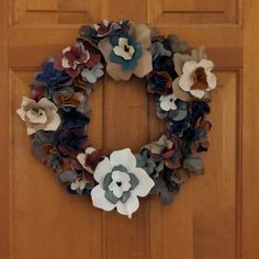 a wreath made out of paper flowers is hanging on the front door to show off it's beautiful colors