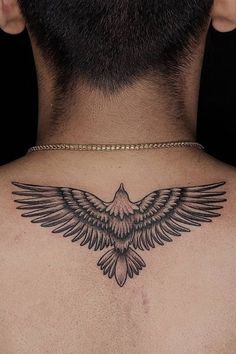 the back of a man's neck with a black bird tattoo on his chest