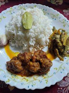 a white plate topped with rice and meat next to an onion on top of it