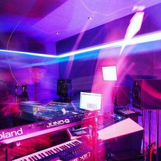 a room filled with lots of musical equipment and sound mixing equipment in front of purple lights