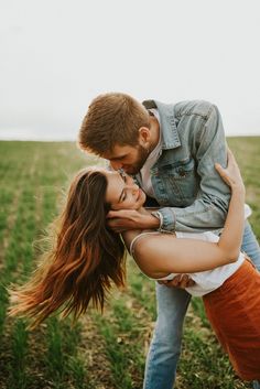 a man and woman kissing in the middle of a field